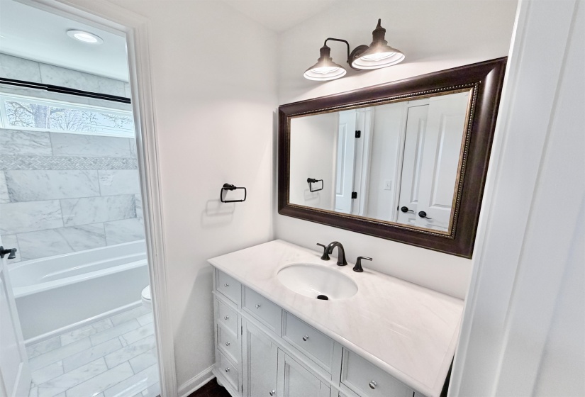 Full bath with soft close vanity, hardwood floors, and large linen closet.  Separate toilet, washtub / shower combination area with marble floors and marble shower surround.