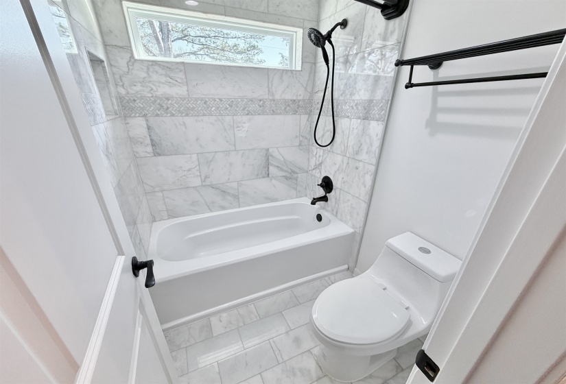 Full bath with soft close vanity, hardwood floors, and large linen closet.  Separate toilet, washtub / shower combination area with marble floors and marble shower surround.