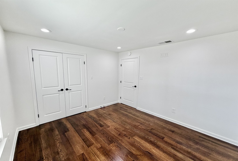 Unfurnished bedroom with recessed lighting, dark hardwood flooring, and a large closet
