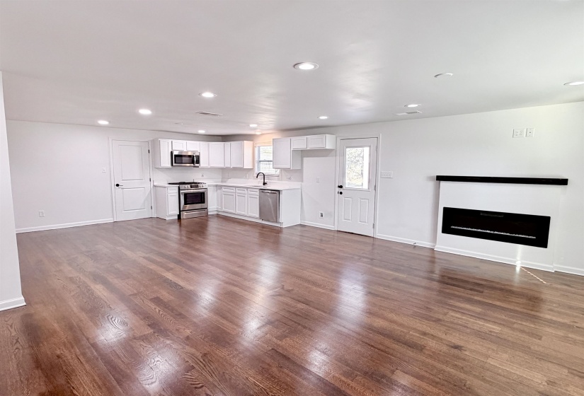 Unfurnished living room featuring dark hardwood floors and recessed lighting