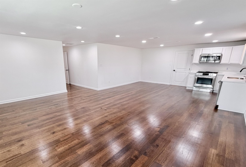 Unfurnished living room featuring recessed lighting and dark hardwood flooring