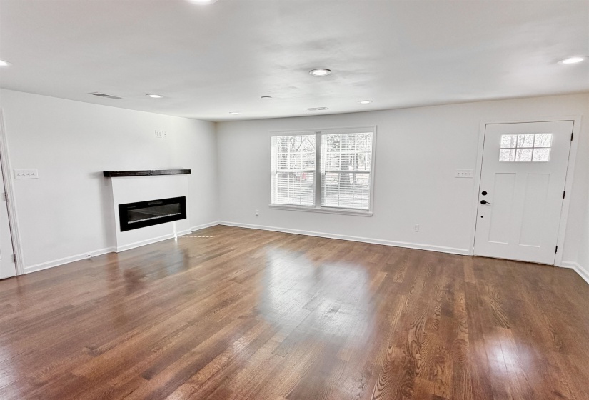 Unfurnished living room featuring a glass covered fireplace, dark hardwood floors, and recessed lighting
