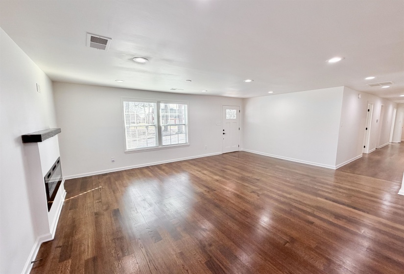 Unfurnished living room featuring dark hardwood  floors, recessed lighting, and a glass covered fireplace