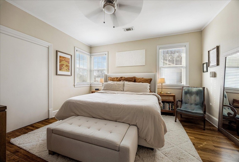 Bedroom featuring wood-finish flooring, a ceiling fan, and two windows with blinds