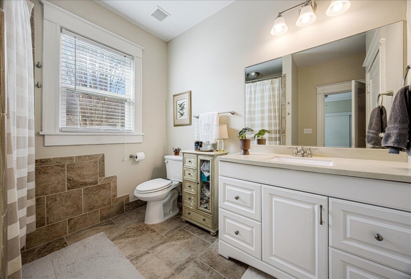 Bathroom featuring a white vanity with a light-toned countertop, a large wall-mounted mirror, and tile flooring