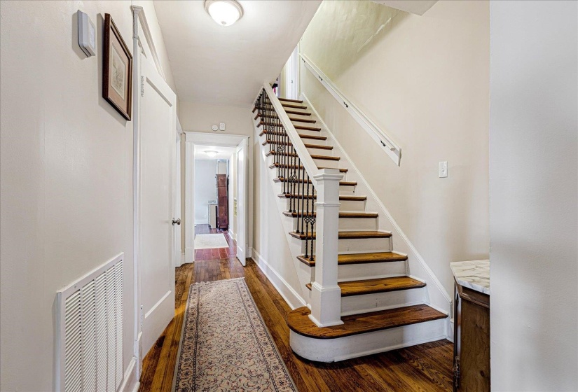 Grand staircase featuring white risers, wood-finish treads, and black iron balusters