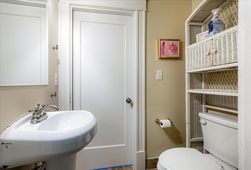 Pedestal sink with chrome faucet, framed mirror, and white paneled door