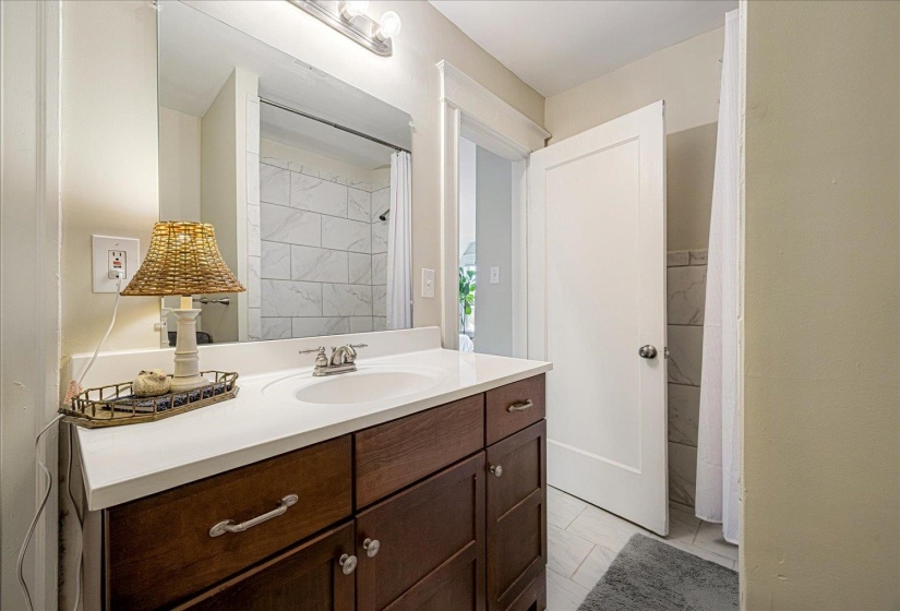 Bathroom vanity featuring a white countertop with an integrated sink, dark wood-finish cabinetry, and a chrome faucet