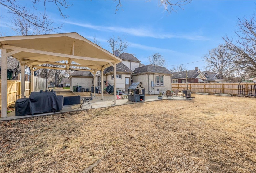 Expansive backyard featuring a large concrete patio, a dedicated covered patio area, and a wood privacy fence
