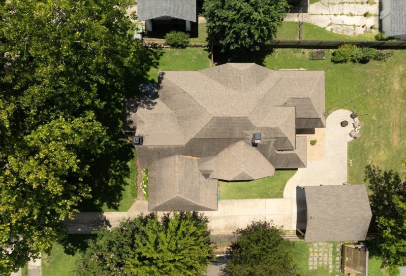 Expansive property featuring a multi-gabled roofline, concrete driveway, detached garage, and a circular patio with seating