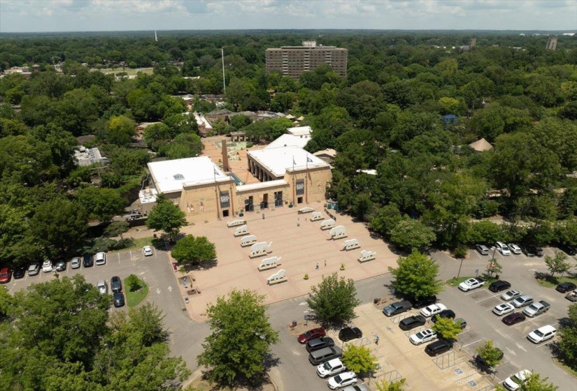 Expansive central plaza bordered by a large structure with a flat roof and surrounding mature trees