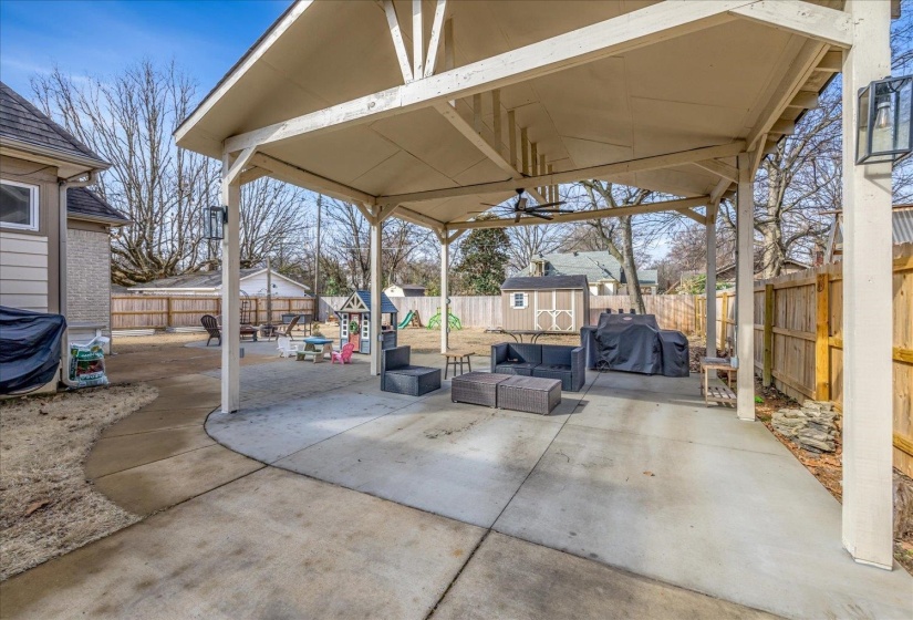 Expansive covered patio featuring a ceiling fan and outdoor lighting, with a concrete surface