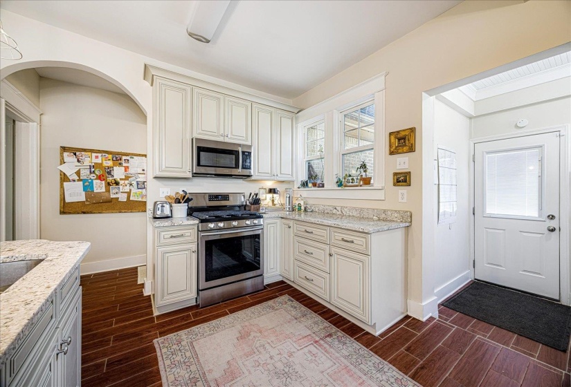 Kitchen featuring white shaker-style cabinetry, stainless steel appliances, light-toned countertops, and wood-finish flooring