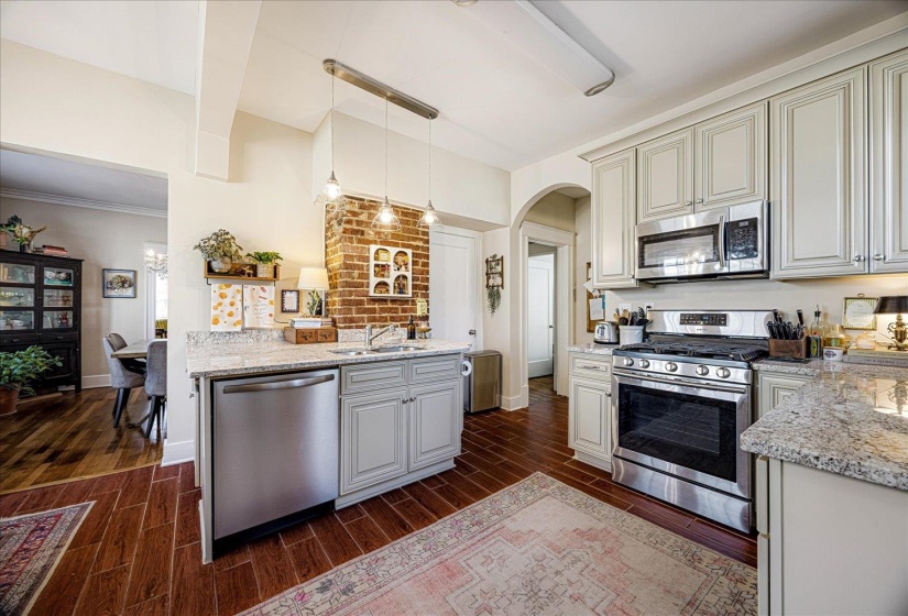 Kitchen featuring wood-finish flooring, light-toned cabinetry, stainless steel appliances, and granite countertops