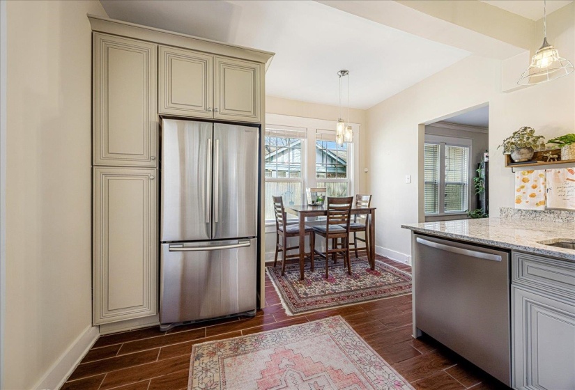 Kitchen featuring wood-finish flooring, light grey cabinetry, stainless steel appliances, and a dining area with multiple windows