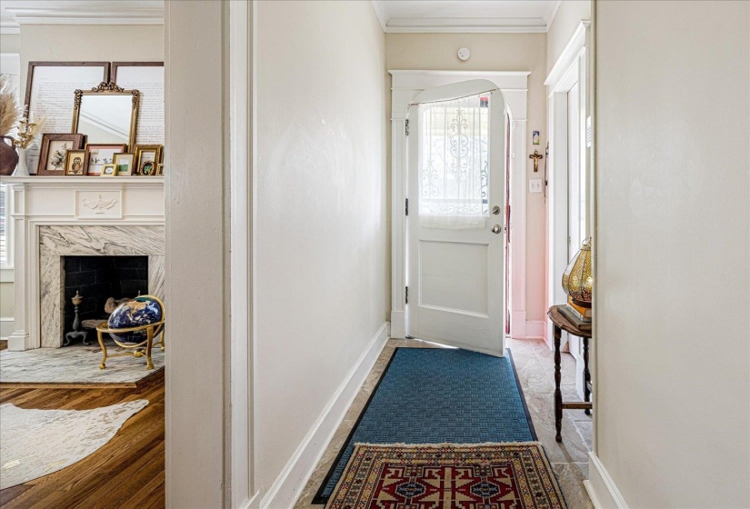Entrance hallway featuring a decorative glass-paneled door, tile flooring, and crisp white trim