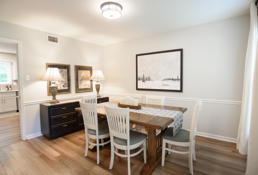 Dining area featuring wood-finish flooring, chair rail molding, and a flush-mount ceiling light
