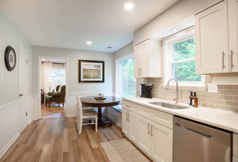 Modern kitchen featuring light wood-finish flooring, white shaker-style cabinetry, and light-toned subway tile backsplash