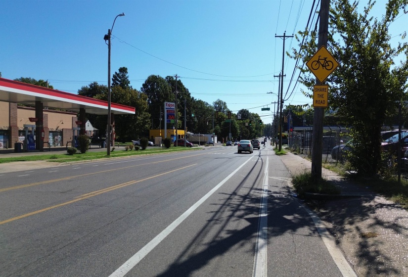 View of asphalt road featuring street lights, sidewalks, and curbs