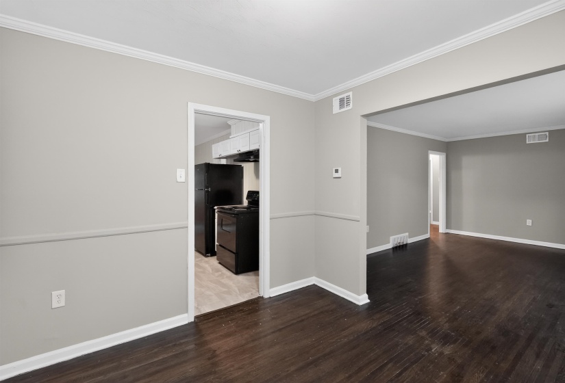 Interior space featuring dark wood-finish flooring and light gray walls with white crown molding and baseboards