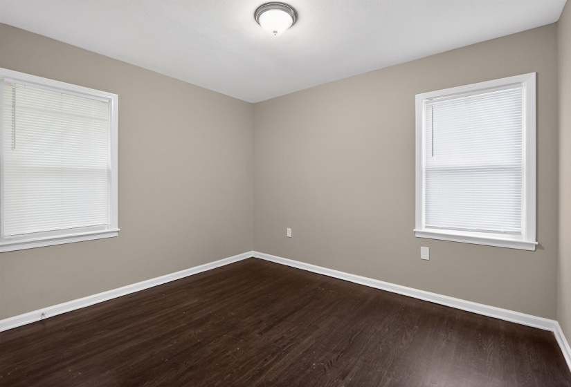 Room featuring rich wood-finish flooring, neutral wall paint, and white trim