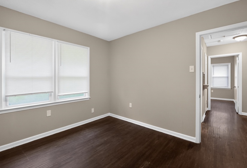 Windowed room featuring dark wood-finish flooring, light tan wall paint, and white trim throughout