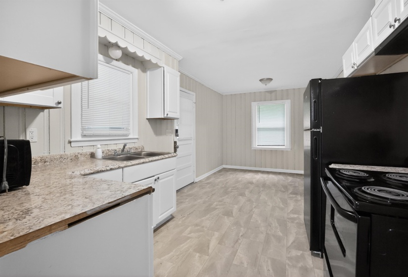 Kitchen featuring light-toned countertops, white cabinetry, and wood-finish flooring