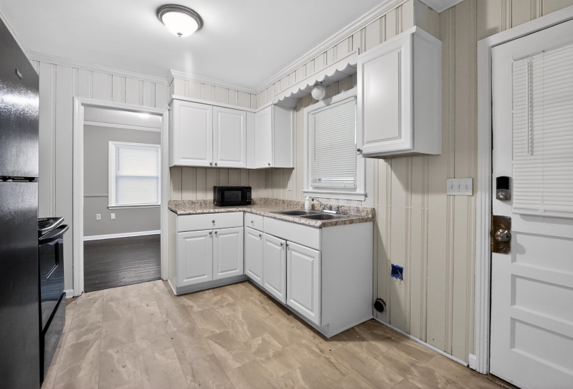 Kitchen featuring wood-finish flooring, white cabinetry, a single-basin sink, and laminate countertops