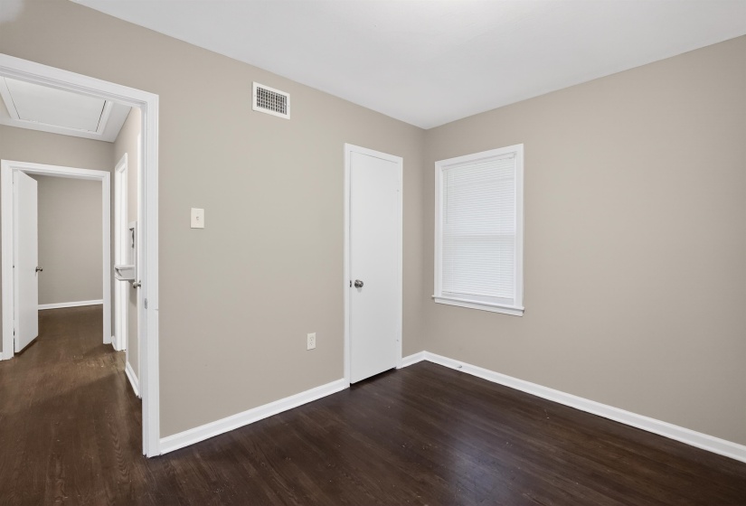 Room featuring wood-finish flooring, neutral wall paint, white trim, and a window with blinds