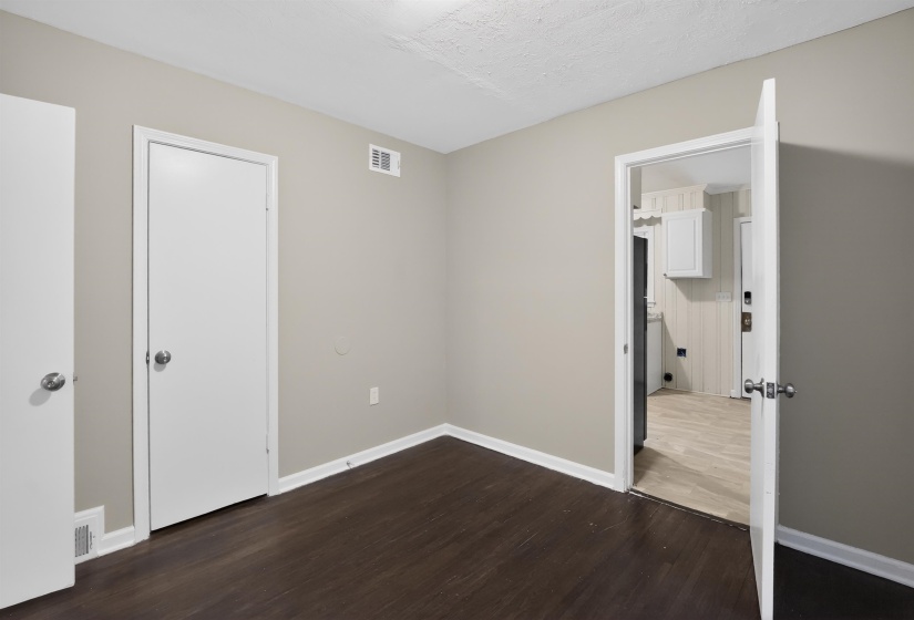 Interior room featuring dark wood-finish flooring, light neutral wall paint, and white trim