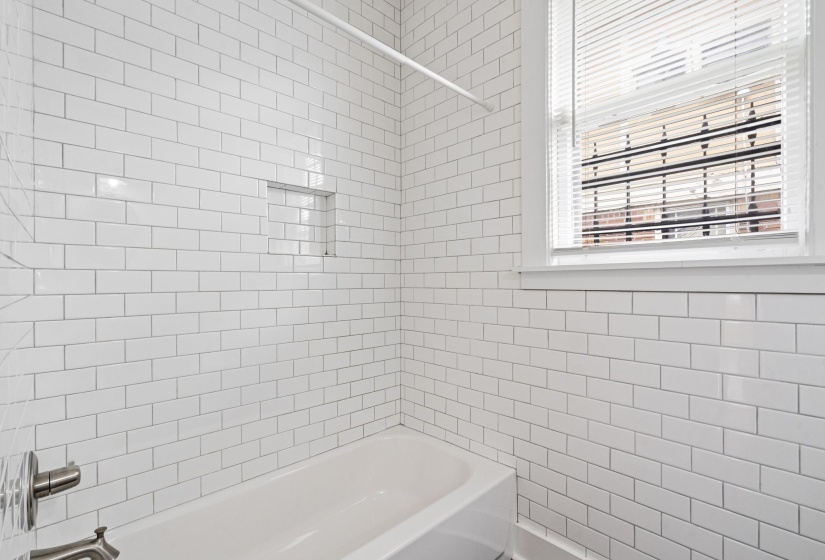 Bathtub and shower combination featuring white subway tile surround