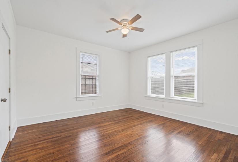 Spacious room featuring wood-finish flooring, white walls, and a ceiling fan