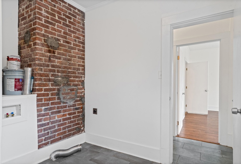 Exposed brick architectural feature with a white baseboard and crown molding