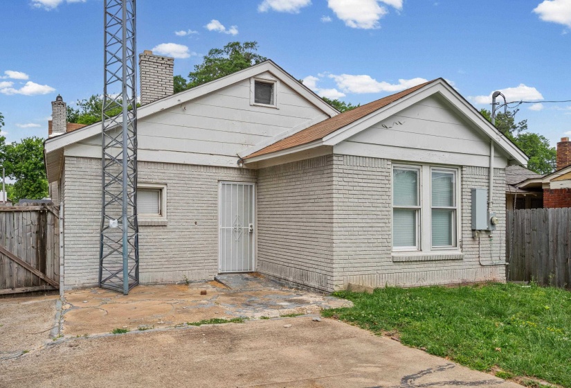 Brick exterior featuring a wood fence, multiple windows, and a metal security door