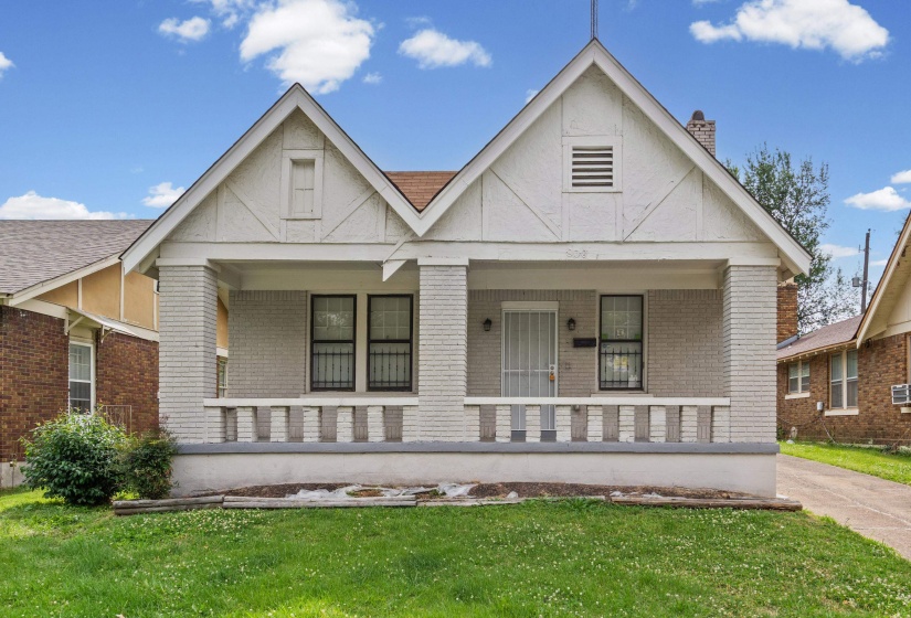 Charming residential exterior featuring a covered front porch with brick columns and a decorative railing