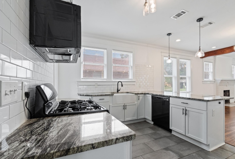 Kitchen featuring granite countertops, white subway tile backsplash, white cabinetry, a farmhouse sink, and a black range with an overhead vent hood