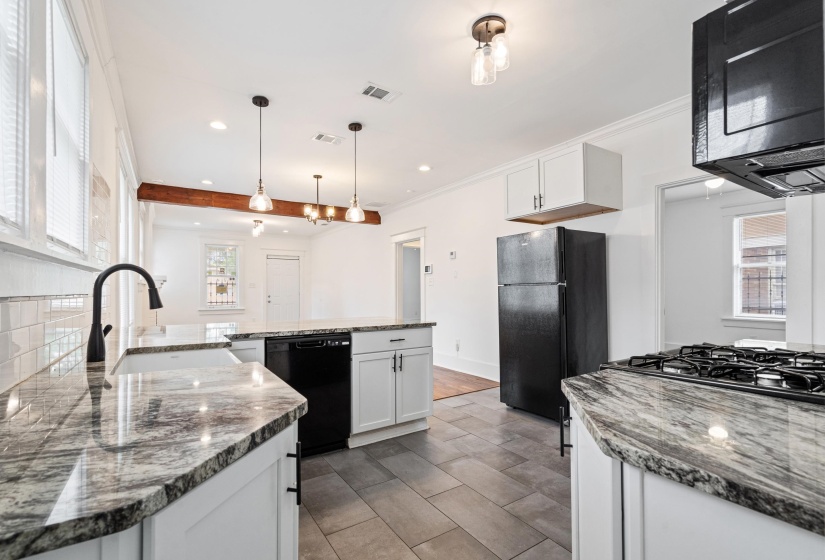 Modern kitchen featuring stone countertops, white shaker cabinetry, and dark tile flooring