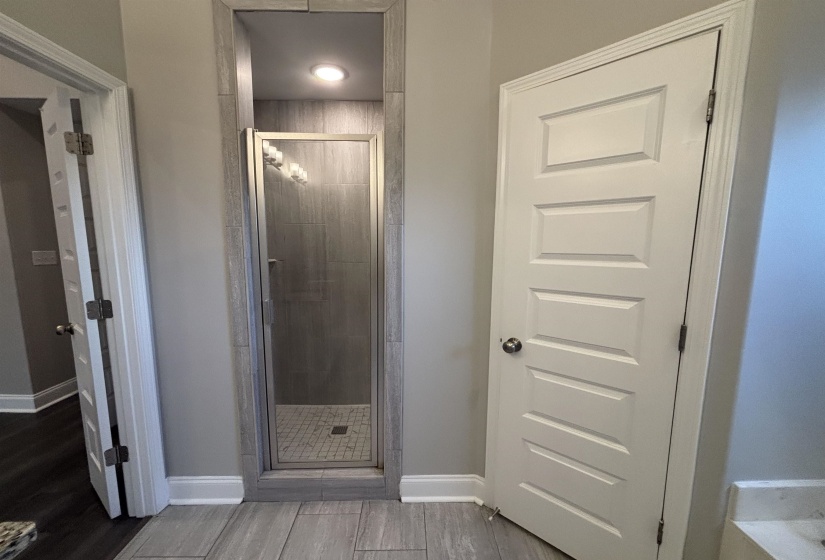 Walk-in shower featuring glass enclosure, tiled walls, recessed lighting, and a tiled shower pan