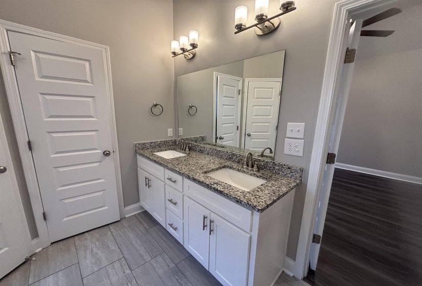 Double vanity featuring white cabinetry, granite-finish countertop, and undermount sinks