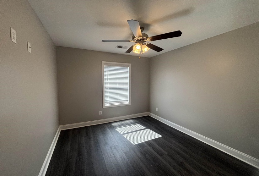 Room with wood-finish flooring, neutral wall paint, and white baseboards