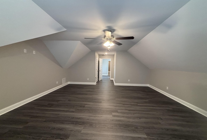 Spacious room featuring sloped ceilings, recessed lighting, and a ceiling fan
