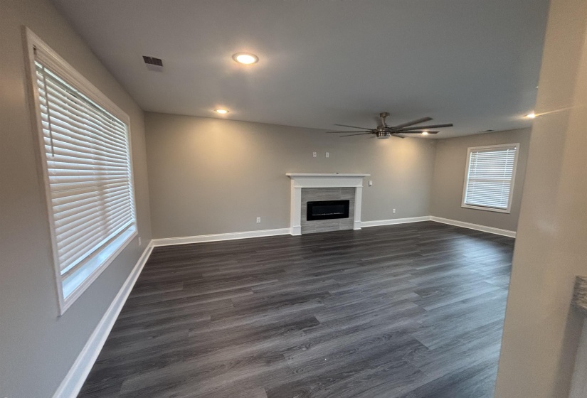Spacious interior featuring wood-finish flooring, a contemporary fireplace with a white mantel, and recessed lighting