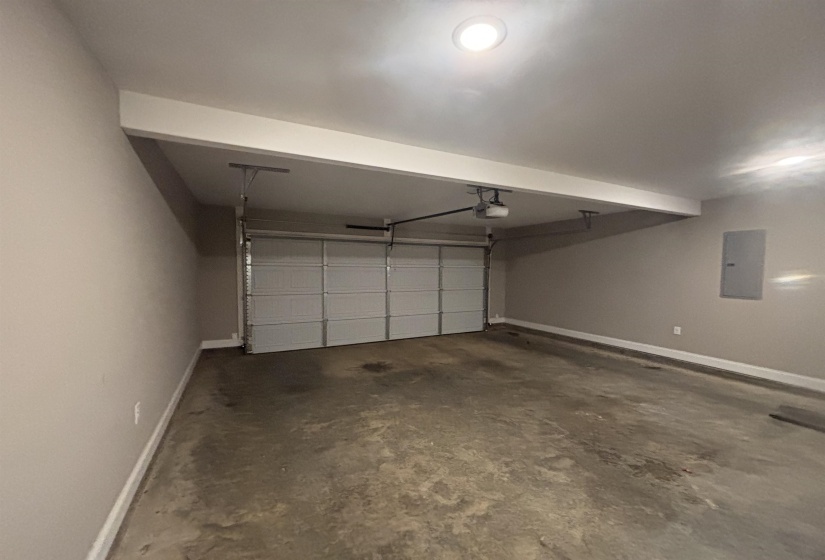 Attached garage featuring a sectional door, concrete flooring, and interior access