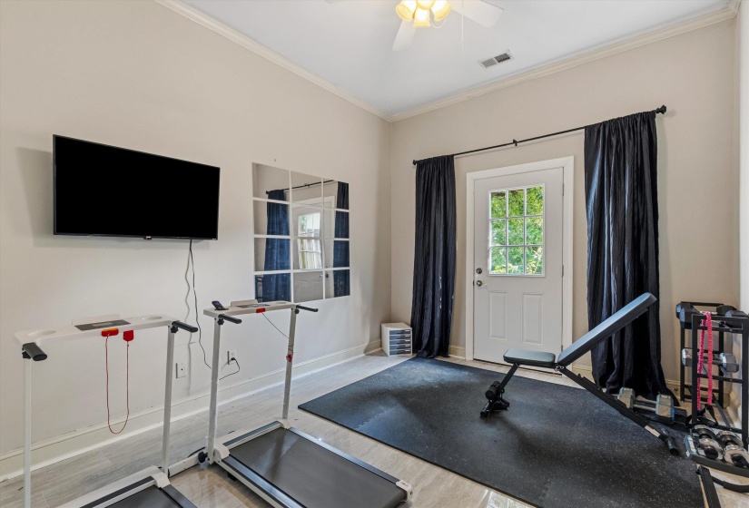 Flexible room featuring light-toned walls, crown molding, and wood-finish flooring