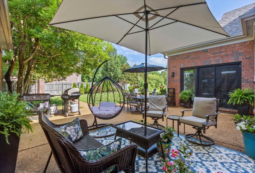 Spacious patio featuring a concrete surface, a brick exterior wall, and double glass-paneled doors