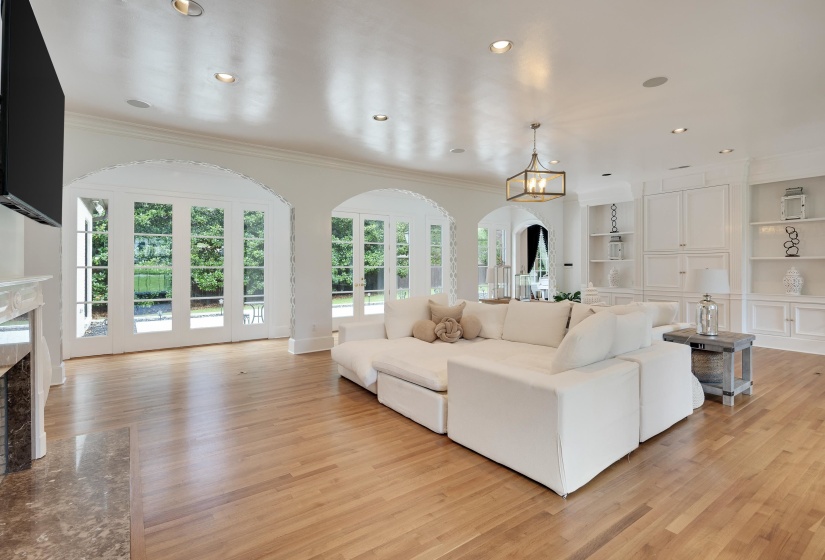 Spacious living area featuring light wood-finish flooring and multiple arched French doors