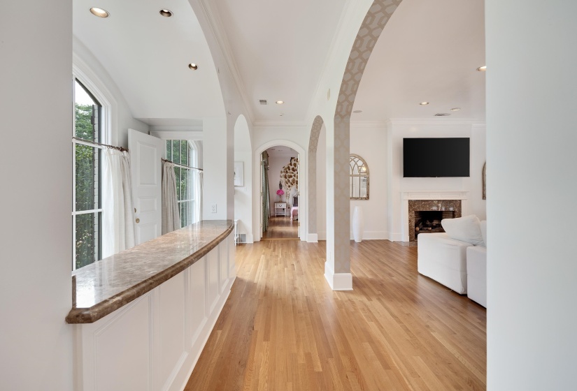 Hardwood flooring extending through arched doorways and a half-wall with a stone countertop