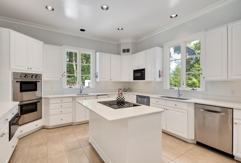 Bright kitchen featuring white cabinetry, light countertops, stainless steel appliances, a center island with an integrated cooktop, and tile flooring