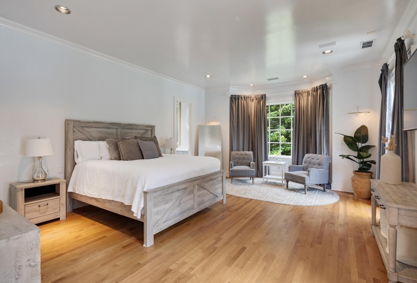 Hardwood flooring throughout a spacious room featuring a recessed window bay with multiple windows