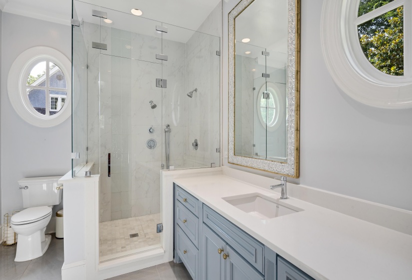 Bathroom featuring a glass-enclosed shower with multiple showerheads, a built-in bench, and a tiled surround